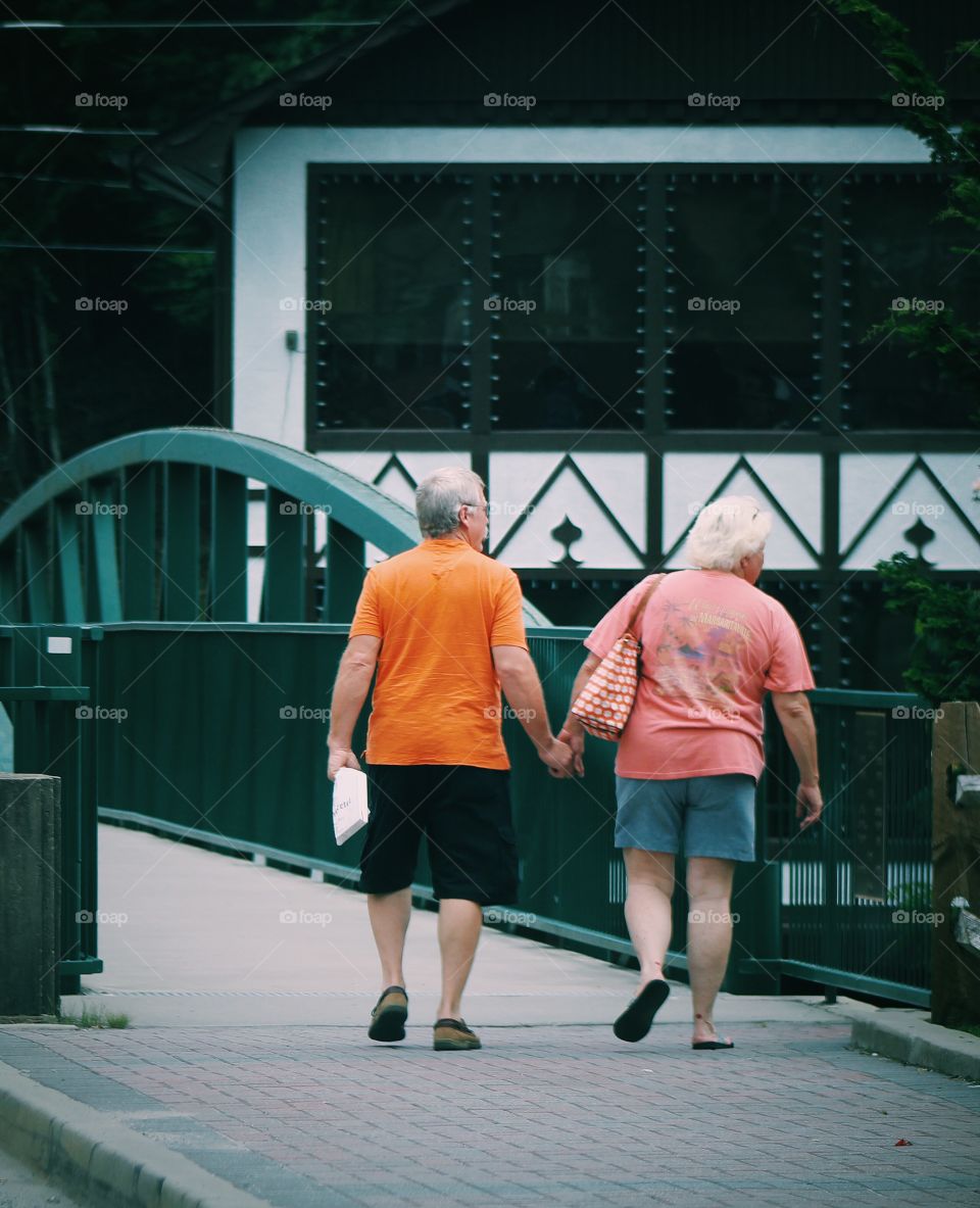 elderly couple in love crossing bridge holding hands and creating memories 