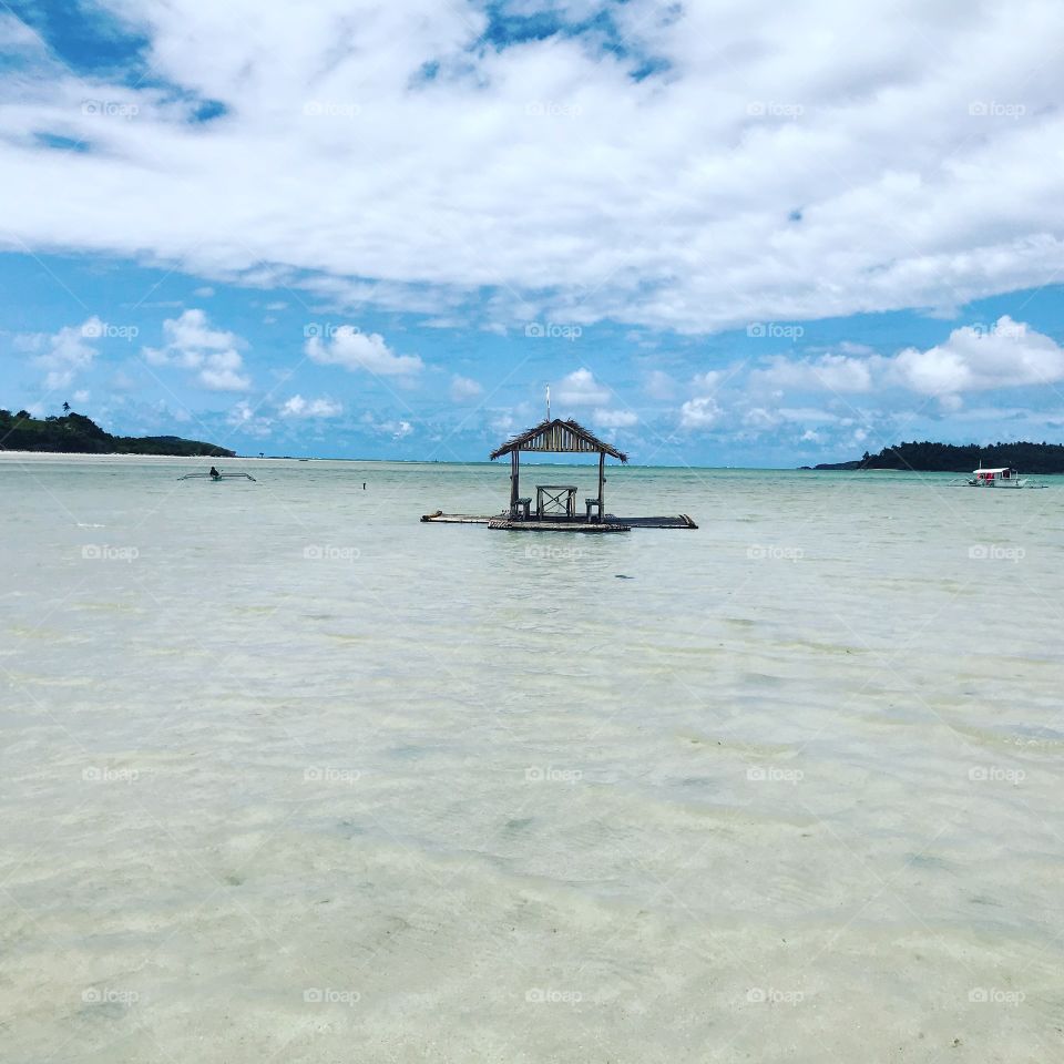 Floating cottage in Manlawi beach, with a beautiful blue sky background struggling from a huge white formation of clouds ...