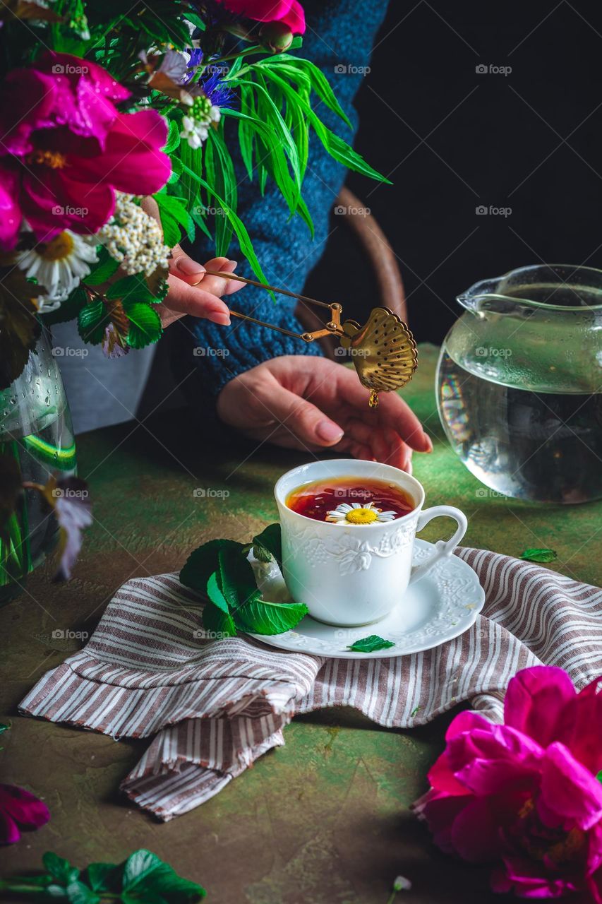 a woman in a warm blue sweater makes tea with chamomile. home Sweet Home. comfort in the home. evening for peace and relaxation. country life and herbal treatment