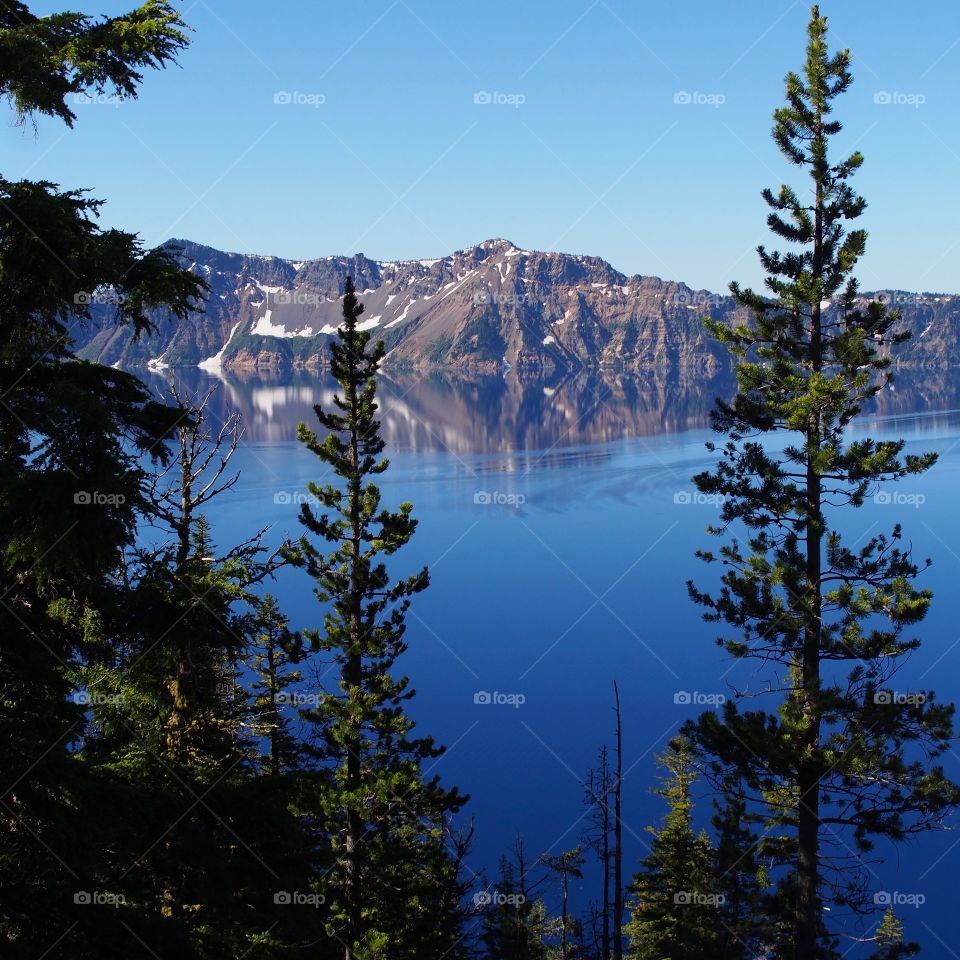 The rugged rim reflecting in the stunning Crater Lake on a beautiful summer morning in Southern Oregon. 