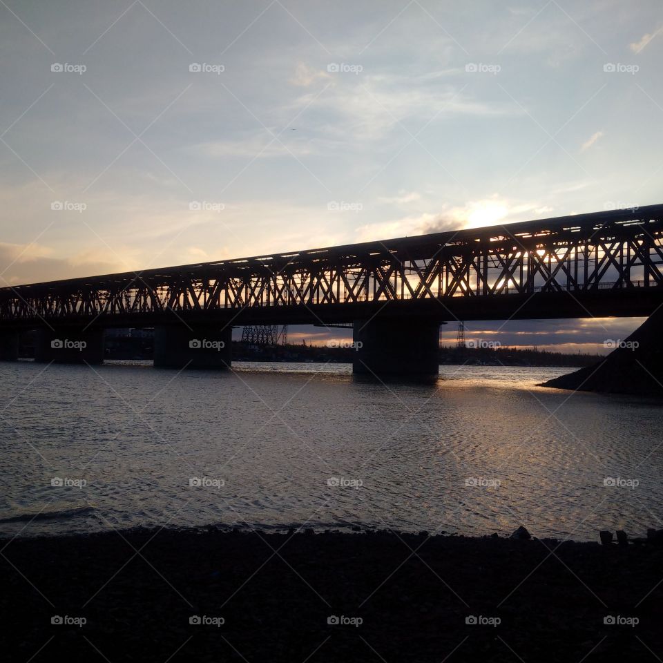railway bridge over the river at sunset