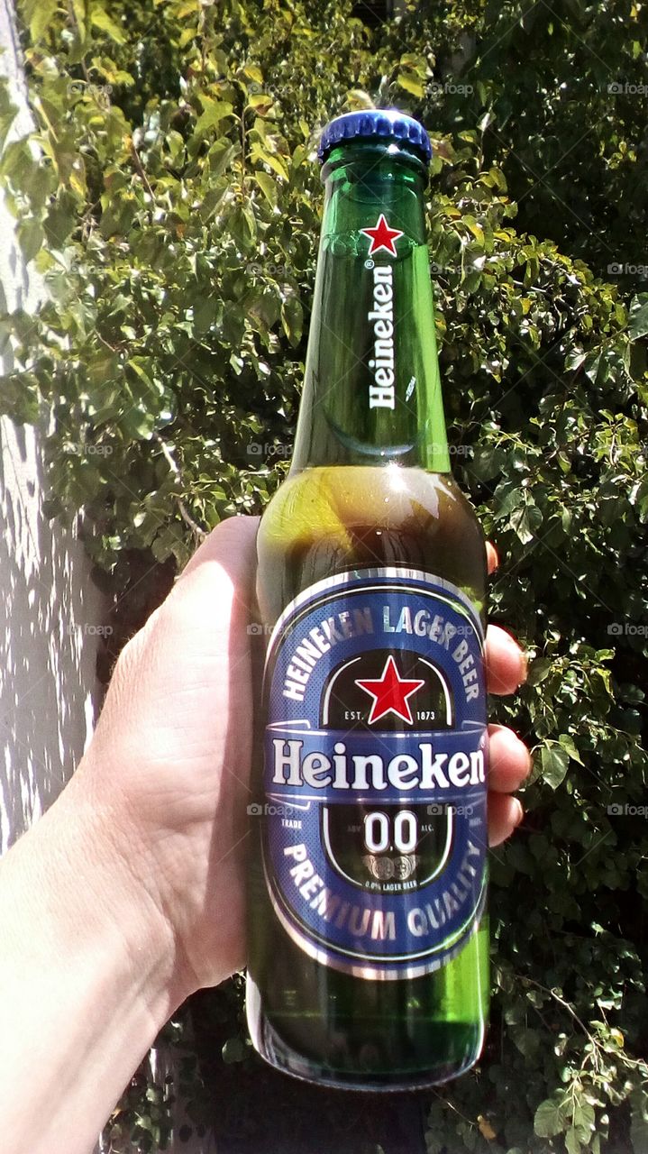 Hand holding one bottle of Heineken00
