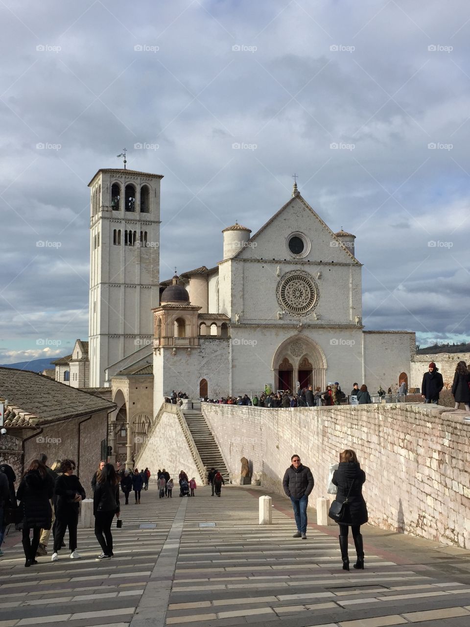 Cloudy day view of the Basilica of St. Francis in Assisi, Italy. Shot from the ramp leading down to lower basilica. December 2017.