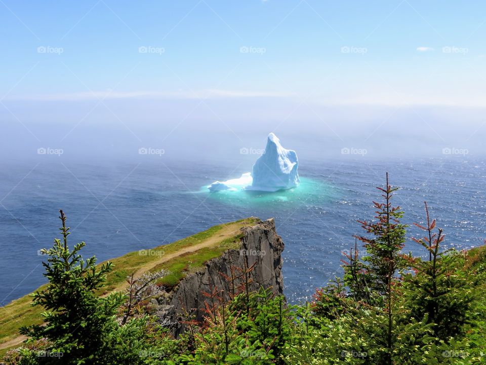 iceberg floating along the Skerwink Trail beside the rugged coast of Newfoundland
 