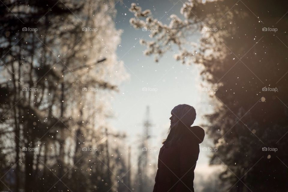 Girl watching snow falling from the trees at sunset, Estonia