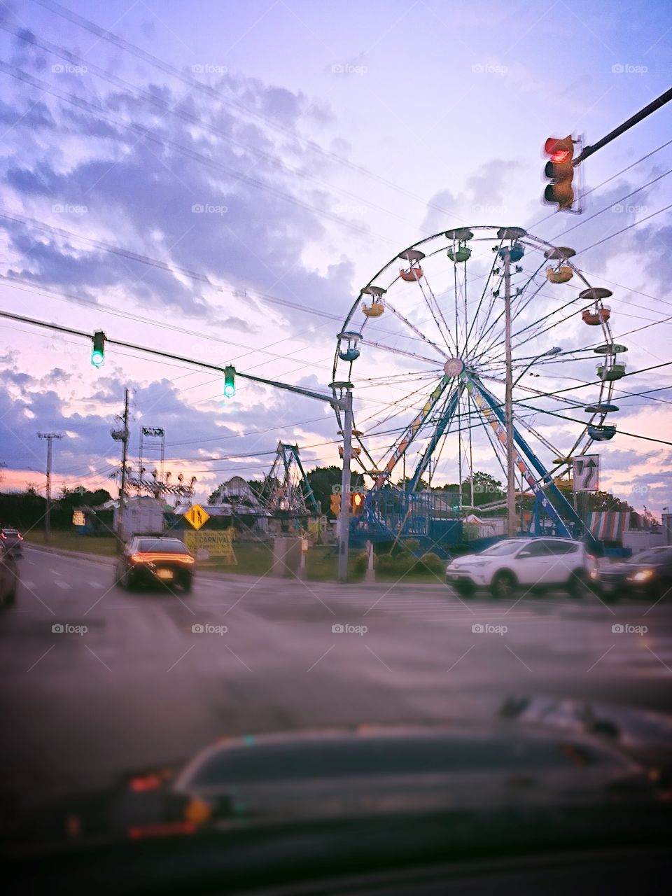 I rode past the colorful ferris wheel at a Carnival in North Smithfield, Rhode Island. The setting sun made the sky look like a painted canvas behind the ferris wheel.