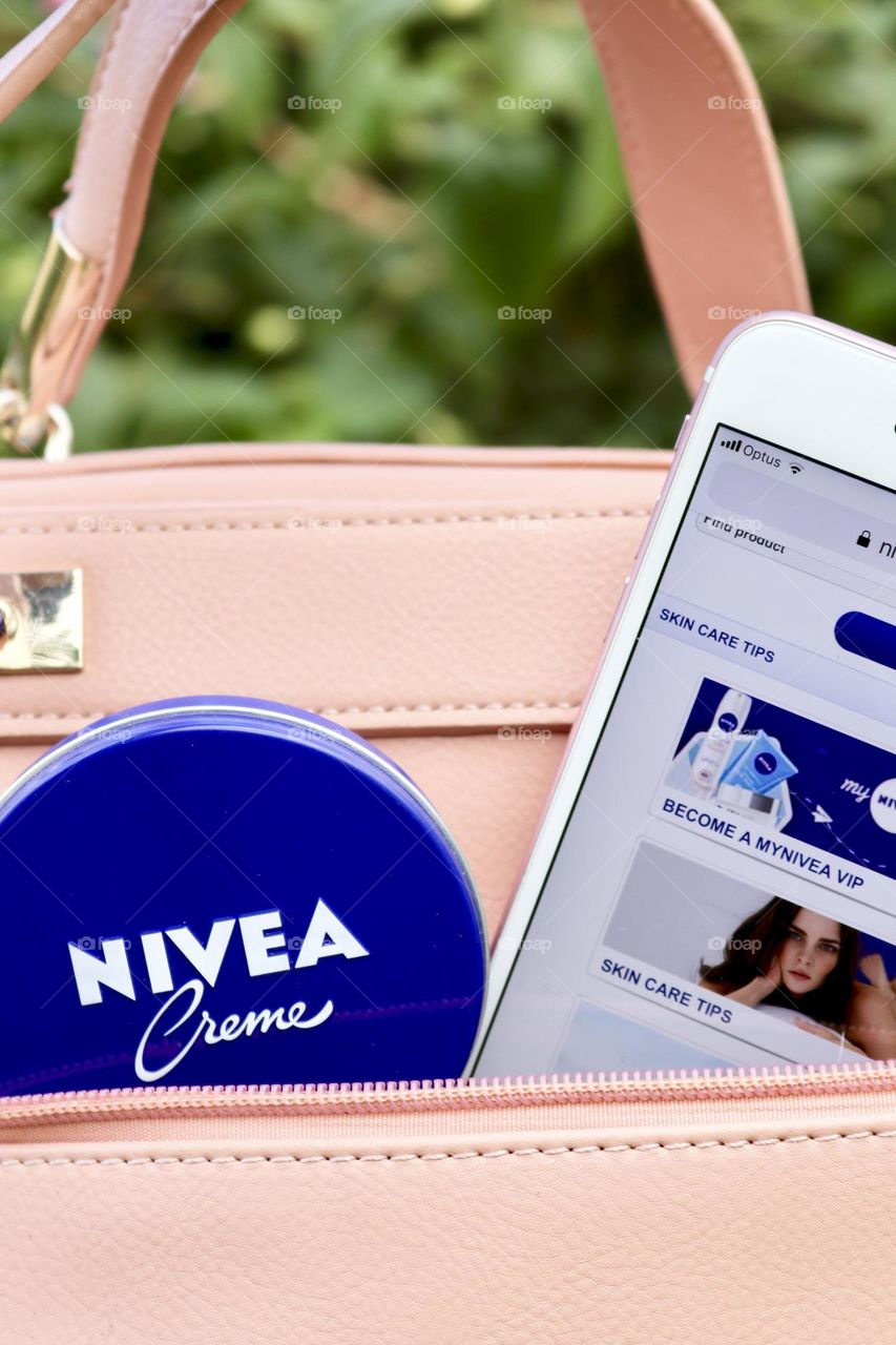 Nivea Creme in the little blue tin, on the go, my favourite take along beauty product, moisturiser Nivea loyalty membership showing on screen of mobile cellular phone in my favourite pink handbag purse 