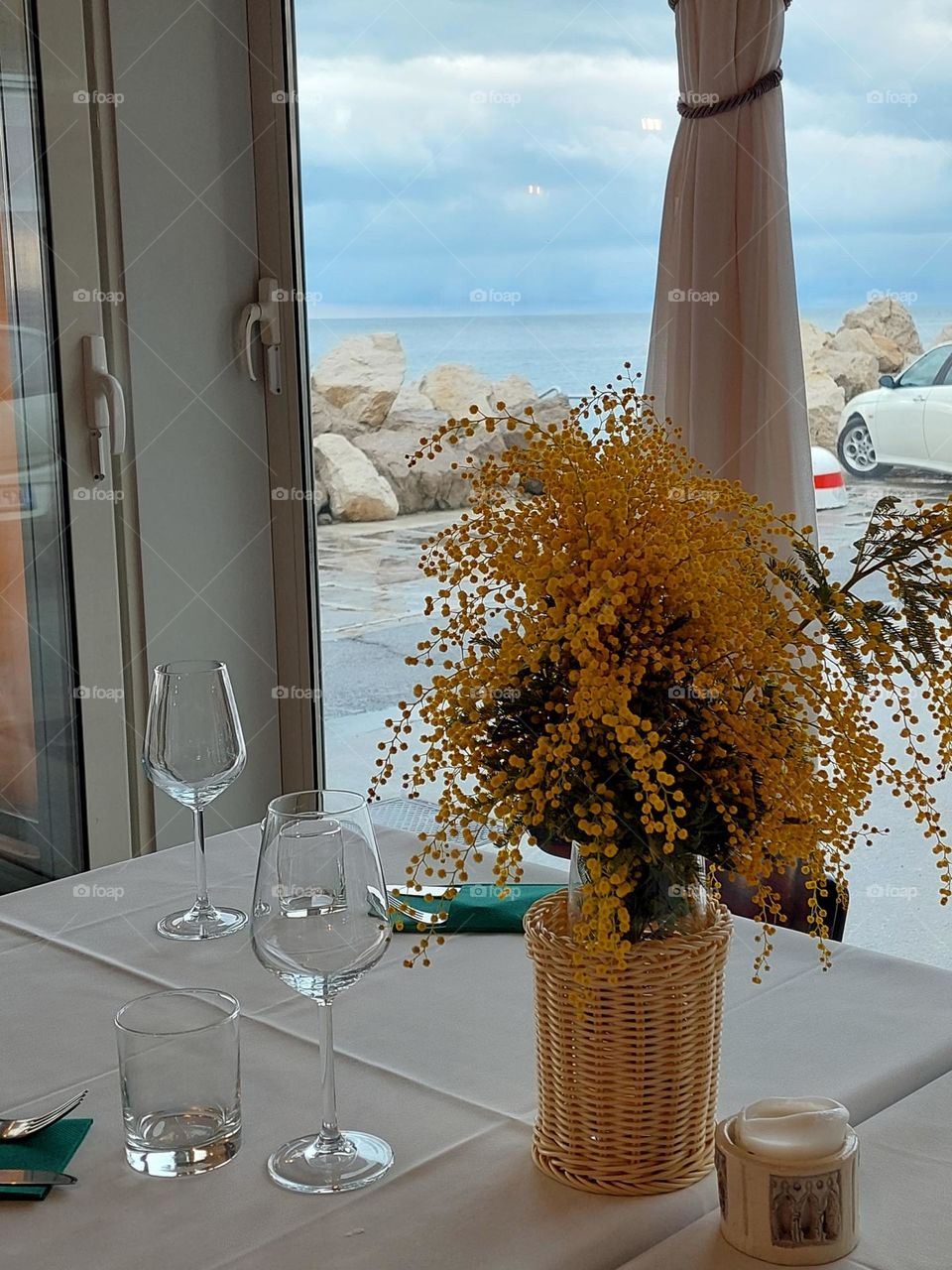 A wicker vase with mimosas on the table by the window