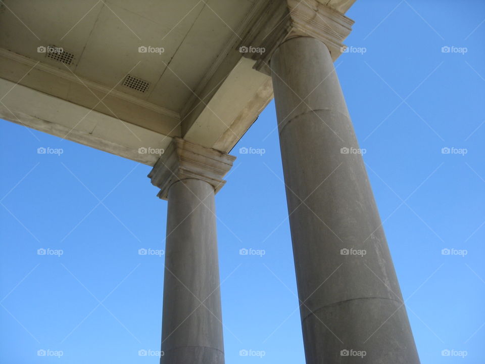 The top corner of the old bank building. Tall columns that reach towards the blue sky, and the lighting was very contrast. 