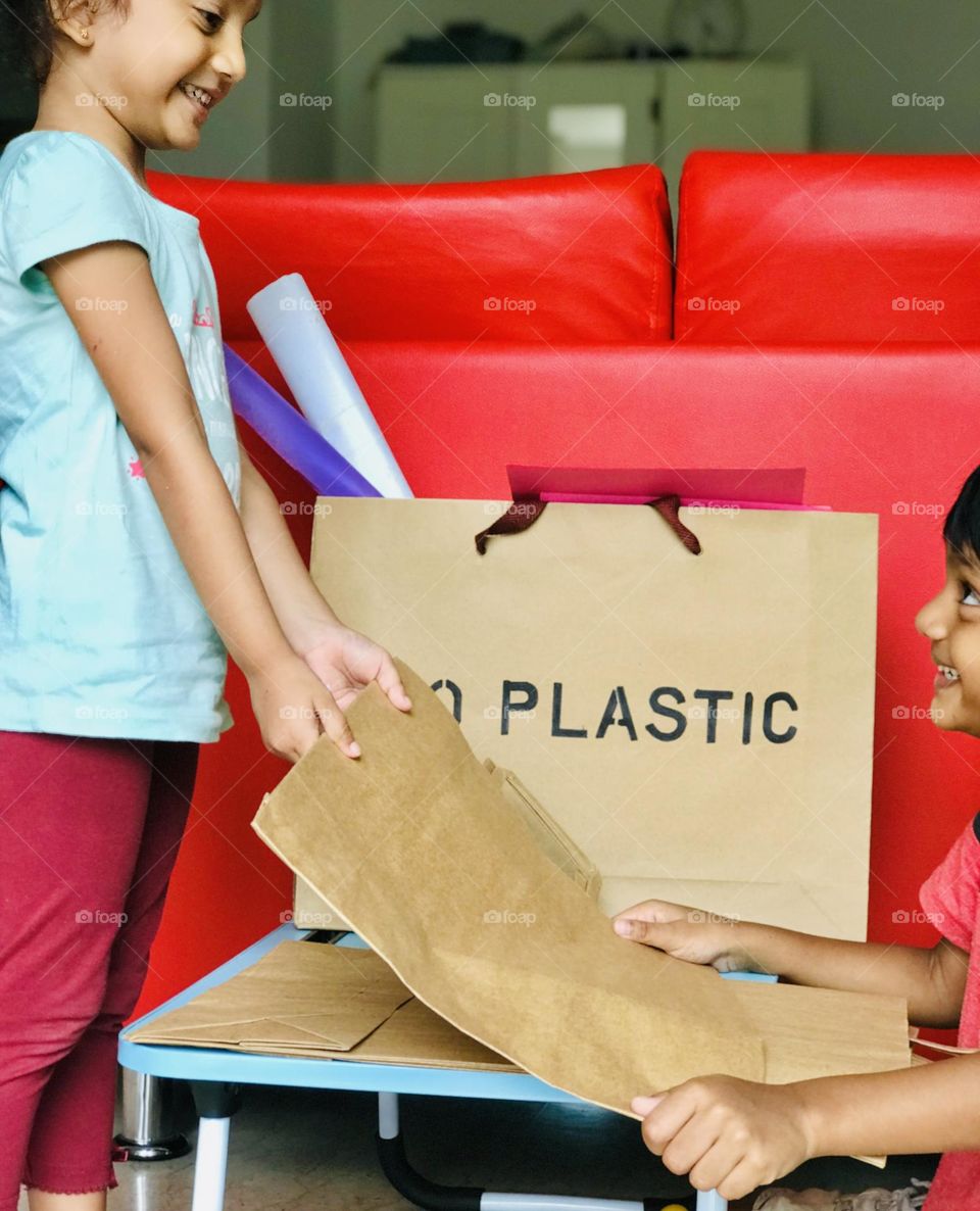 Kids sharing eco friendly paper bags each other with cute smile.