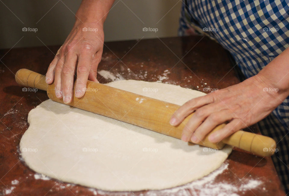 A woman rolling out dough with a rolling pin