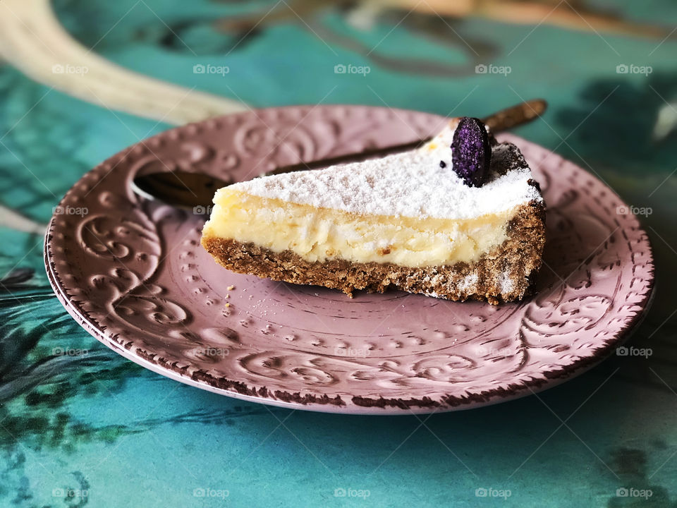 Slice of fresh creamy cheesecake on pink plate on blue table 