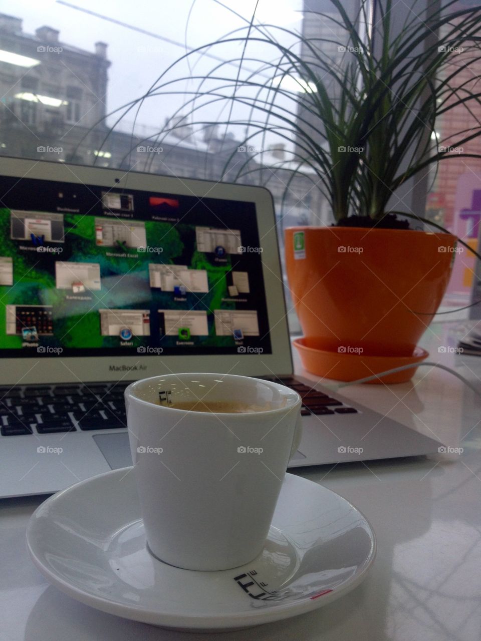 Morning espresso in front of laptop and a flower in pot on a table