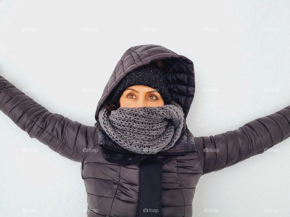 portrait of woman lying on the snow looking at the sky