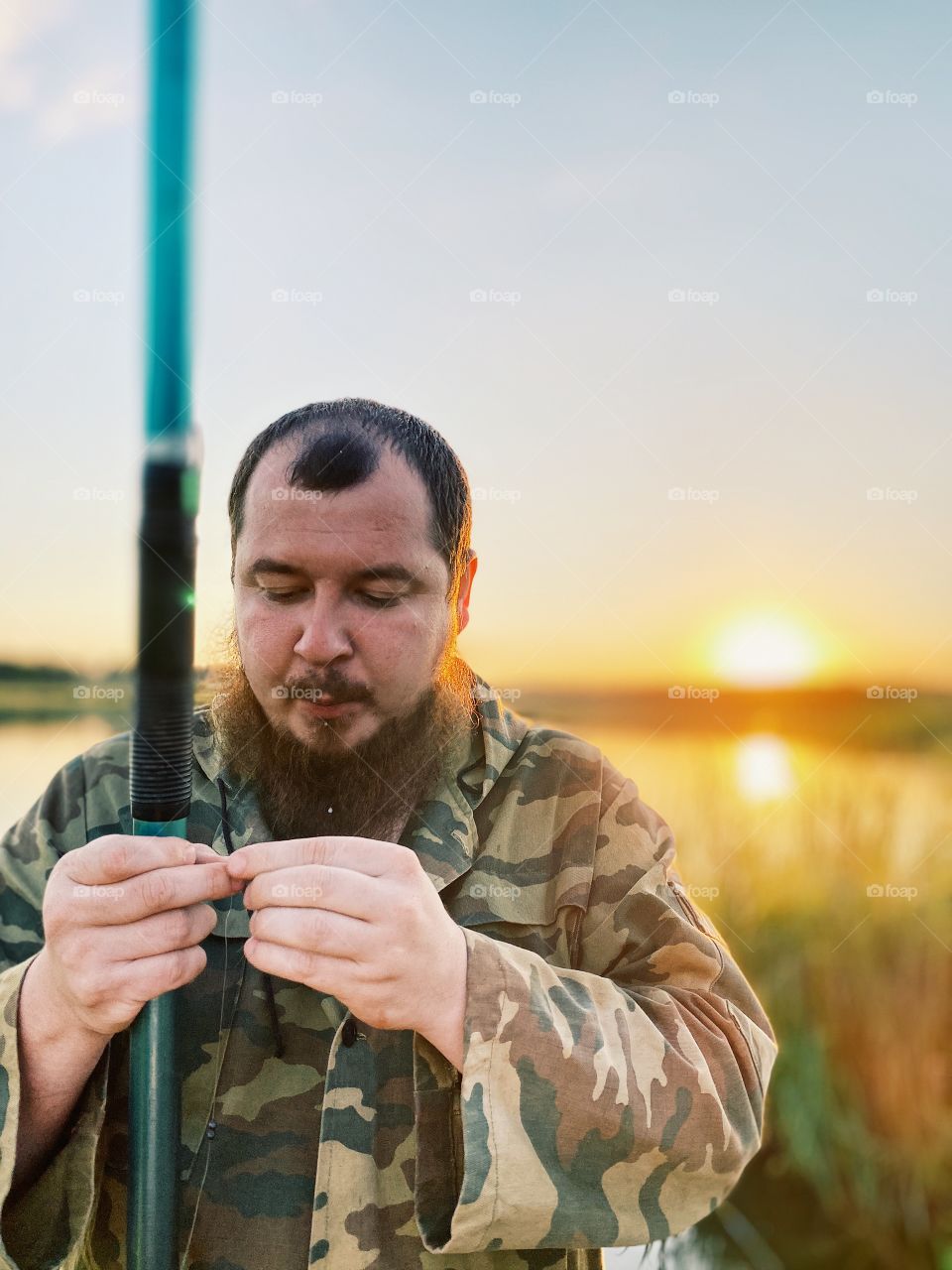 Bearded guy is fishing on the lake