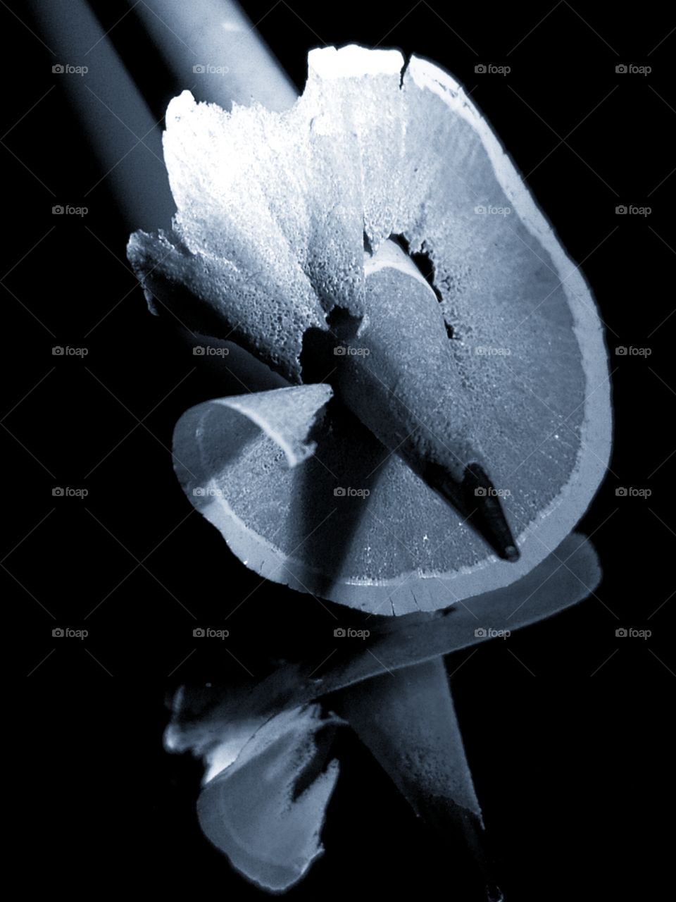 A graphite pencil with a thin rod on which its shavings are wound.  Reflection in the mirror