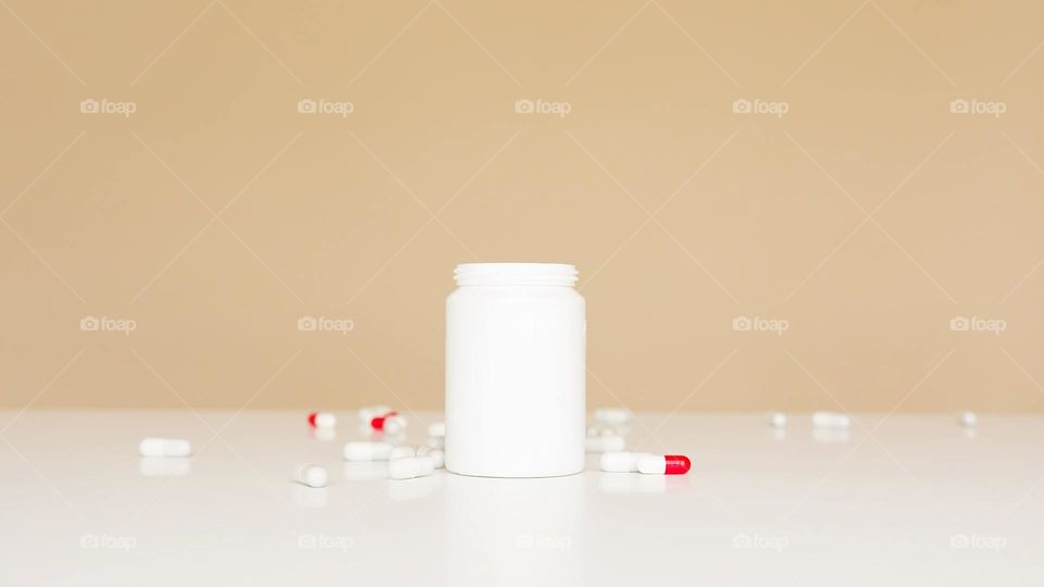 Red capsules on the tables with an empty with bottle.