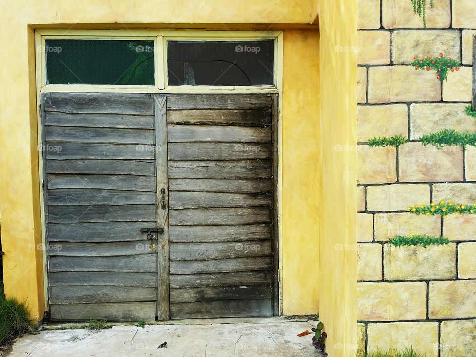 Old wooden door with art orange wall.