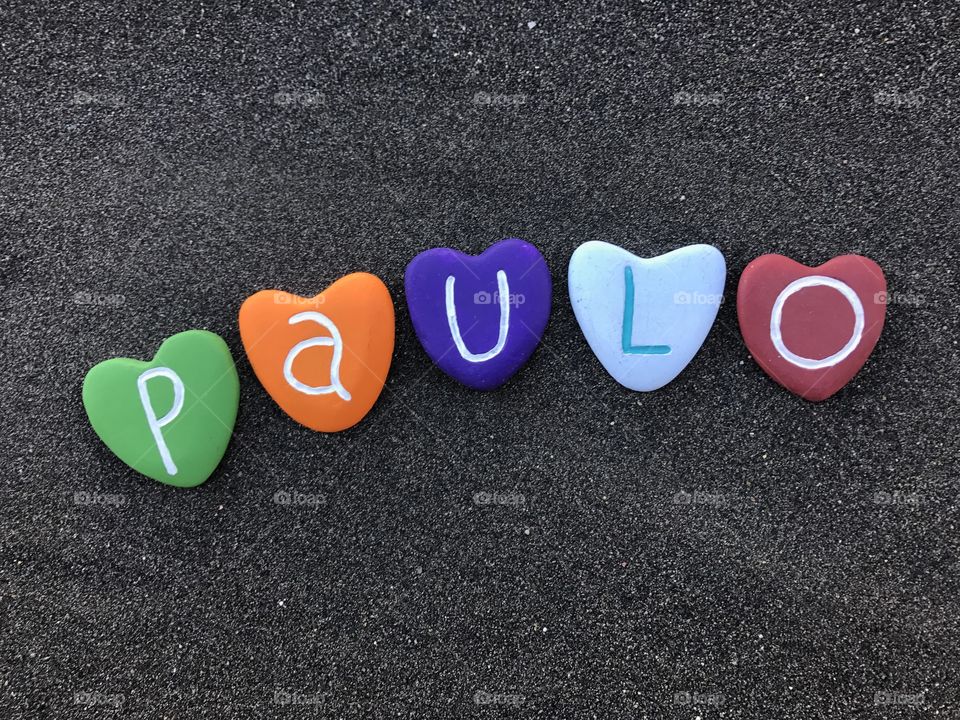 Paulo, masculine name with colored heart stones over black volcanic sand