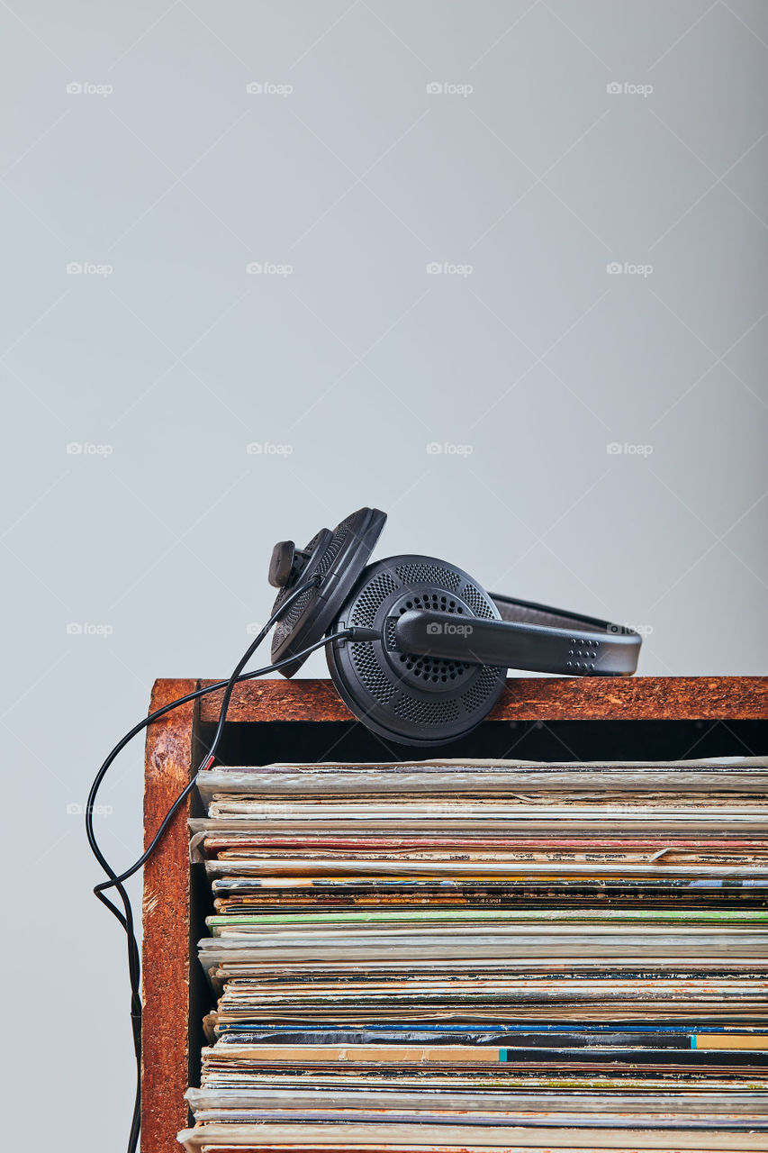 Stack of many black vinyl records and headphones put on the top of stack. Candid people, real moments, authentic situations