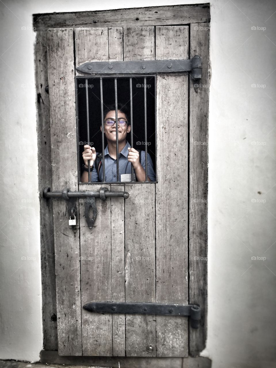 Boy looking through window of old door