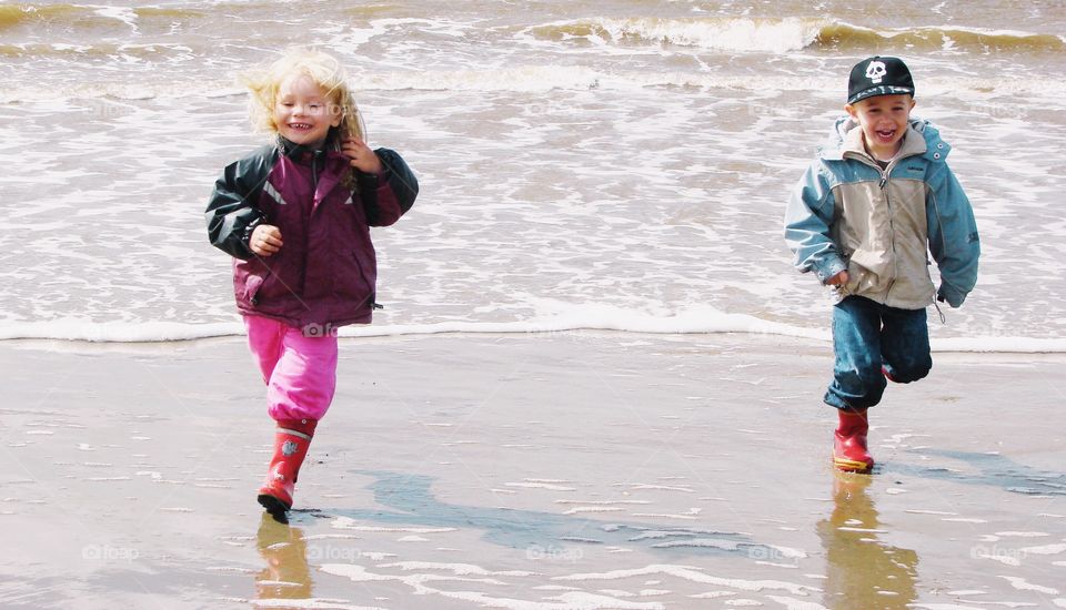 Two children. Two children playing with the vawes at the ocean