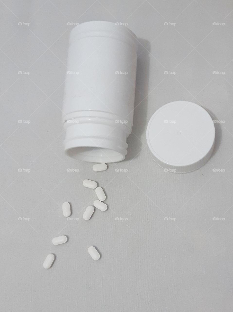 White plastic medical container and capsule pills against on white background, top view