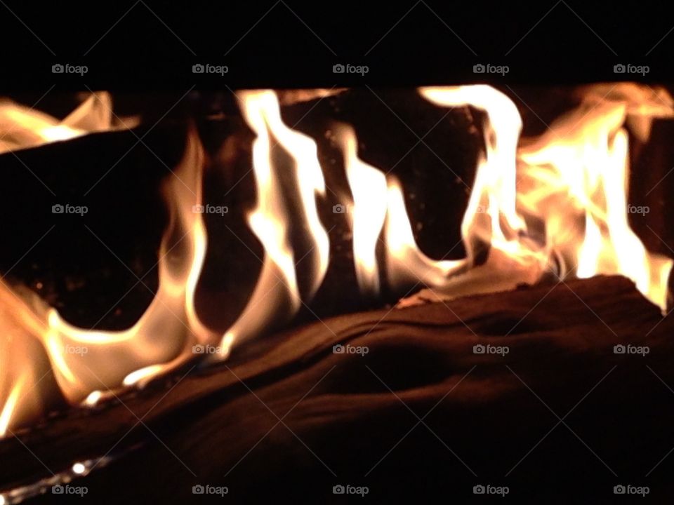 Staying warm on a cold winters night by a crackling fire. The flames are tickling at the logs in this fireplace. 
