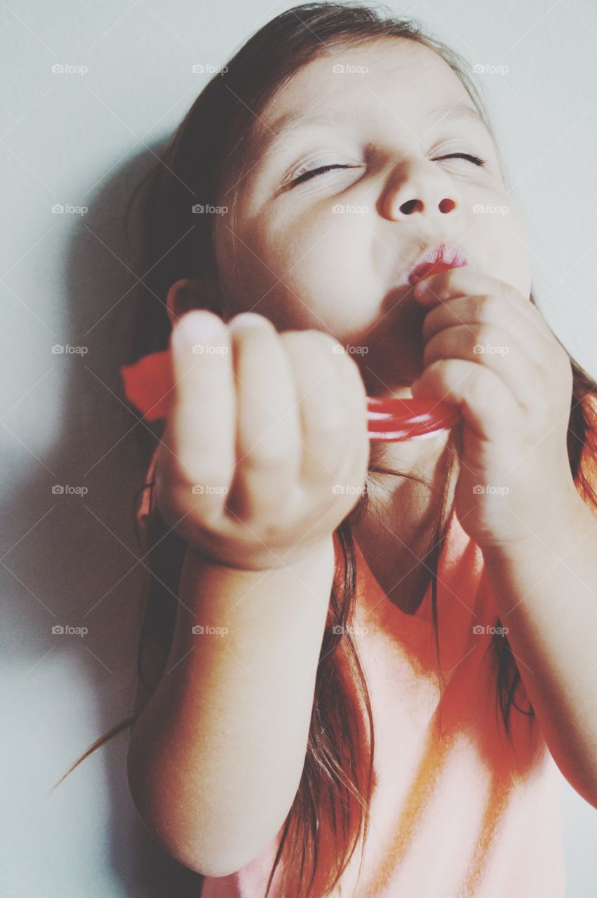 Close-up of a girl enjoying sticky red candy