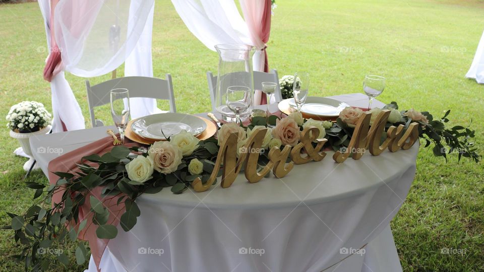 Outdoors Wedding reception bride and groom table setting under tent on a sunny day