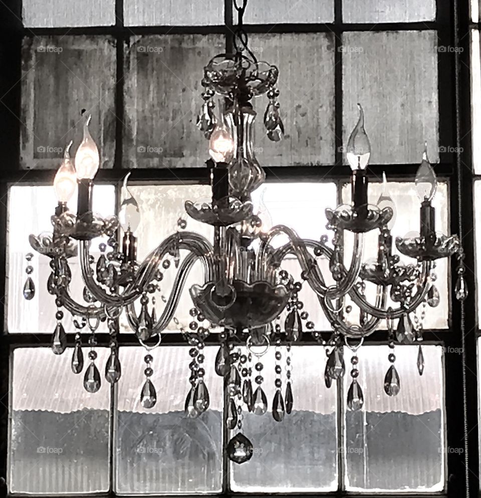 An old chandelier hanging in front of some old factory windows