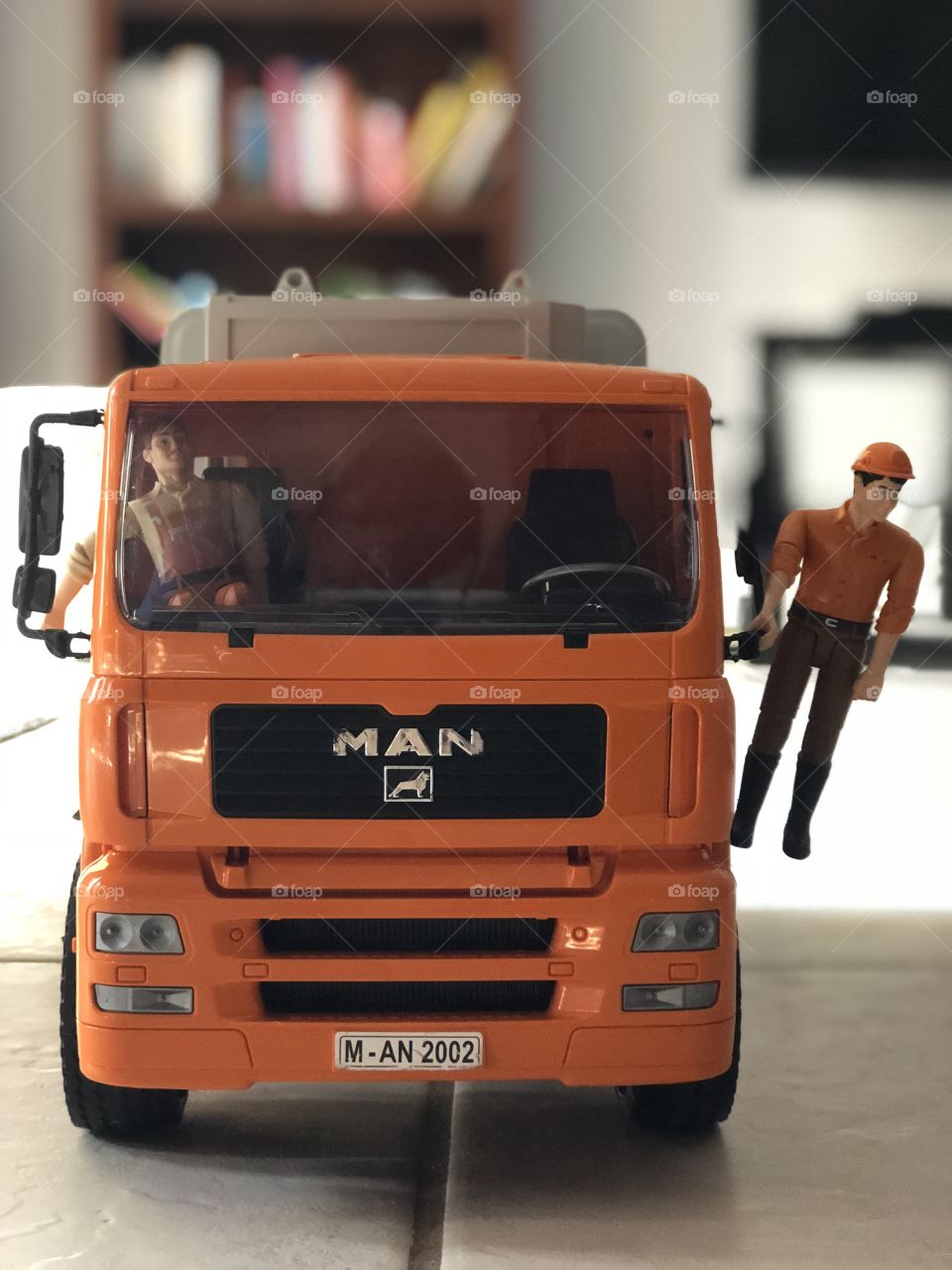 The Bruder man is picking up garbage with his garbage truck