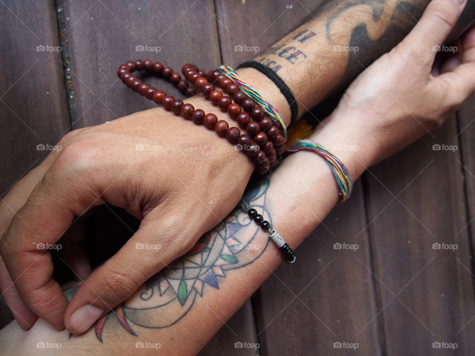 Close-up of person's hand with tattoo and beads