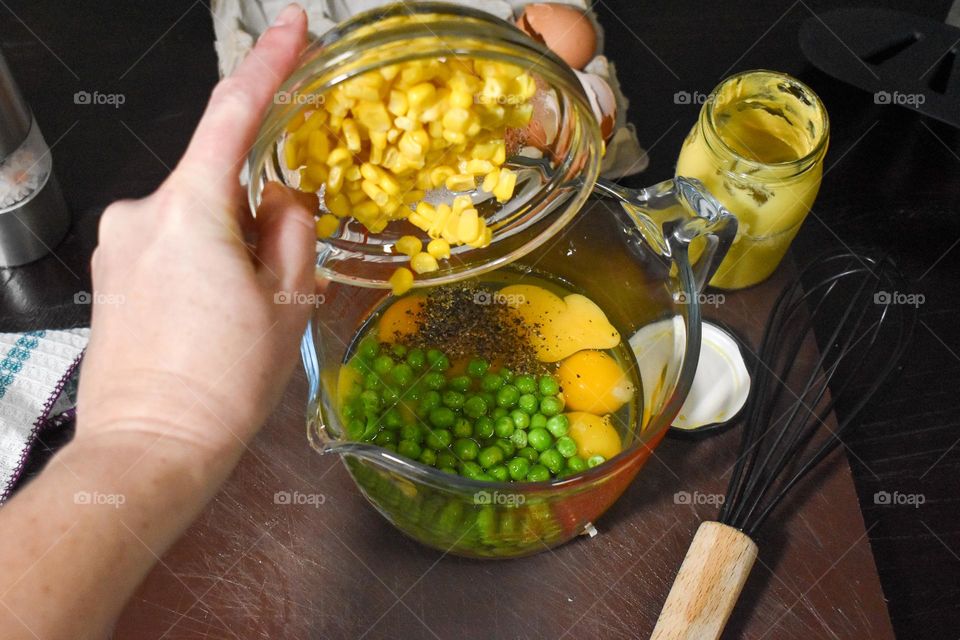 Homecooking cooking Frittata at home and adding and mixing ingredients and removing the Frittata from the pan for cutting and serving on a white plate with tomatoes. Healthy home cooking in kitchen. Breakfast and lunch food preparation.