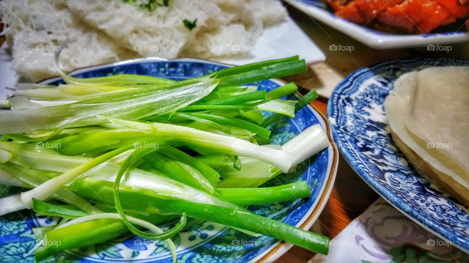Shallot or scallion pieces sliced into thin strips on a plate. Usually served as an accompaniment to many Chinese culinary dishes.