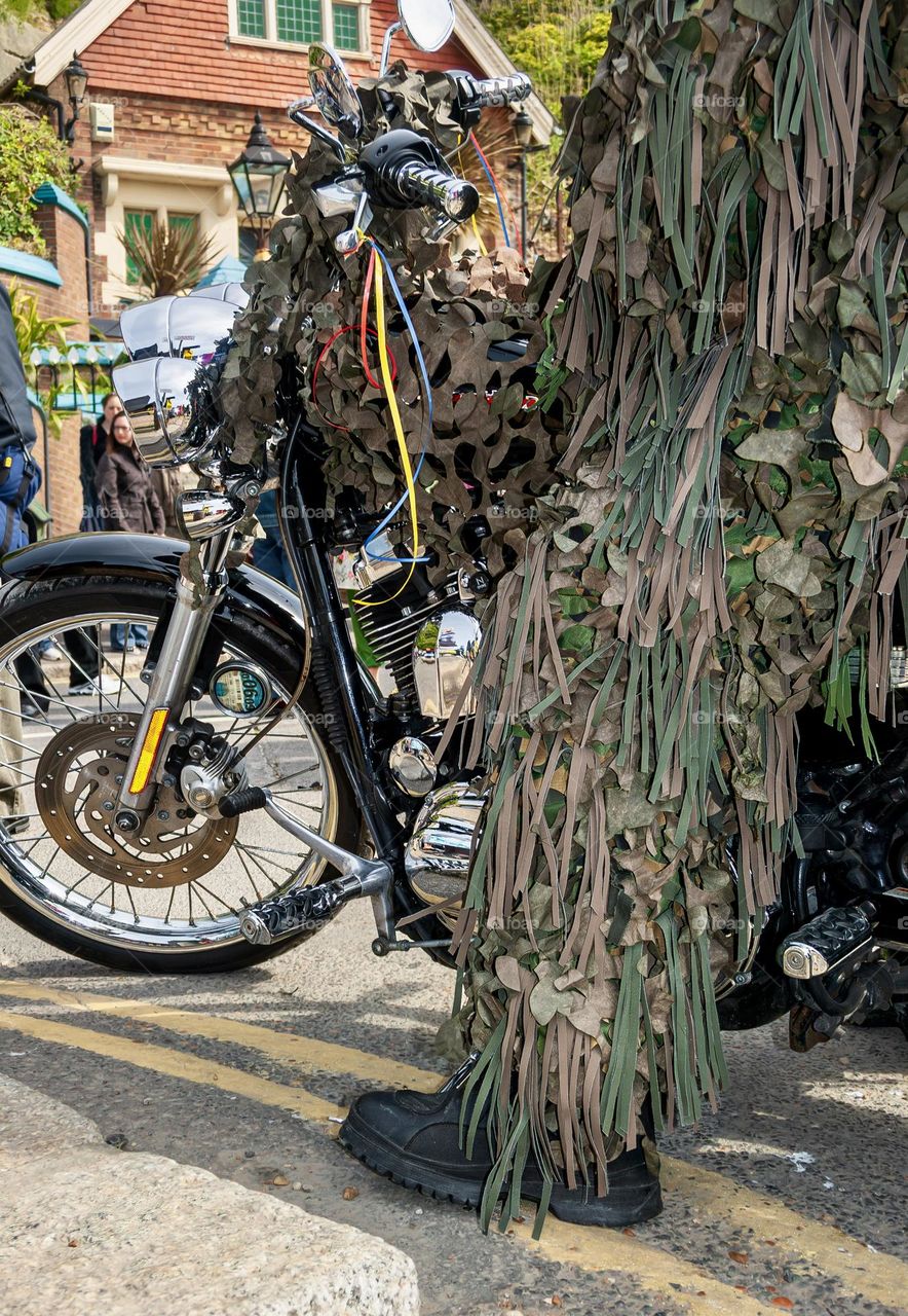 Man dressed up in a ghillie suit on a motorbike, taking part in 2 May Day traditions in Hastings - Jack in the Green and the A21 May Day Run.