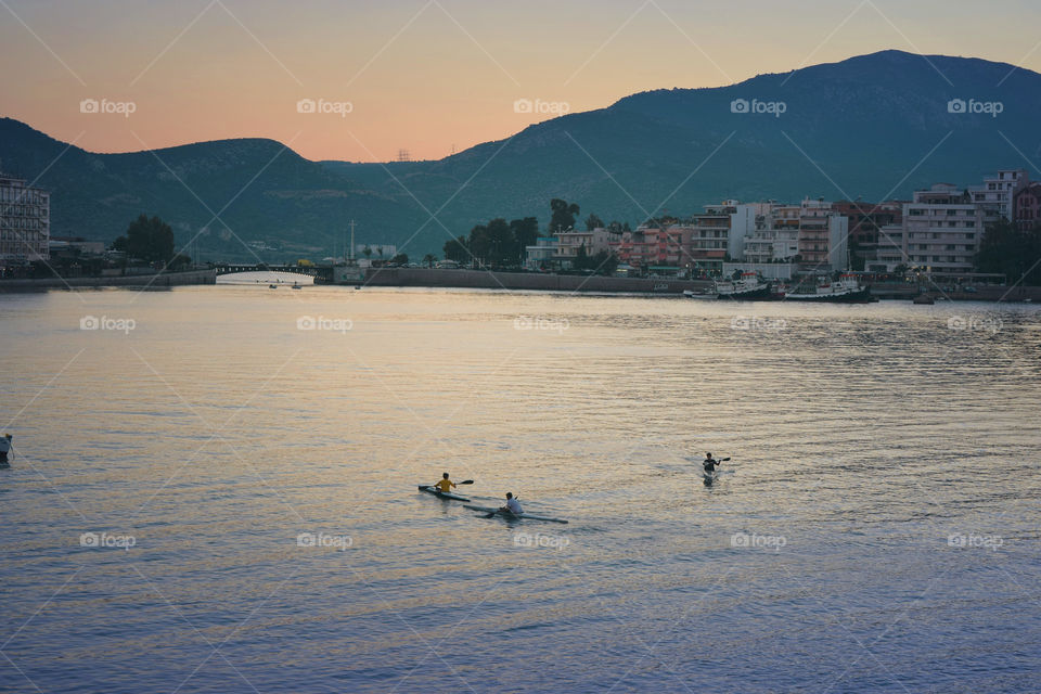 Children canoeing over the river at sunset