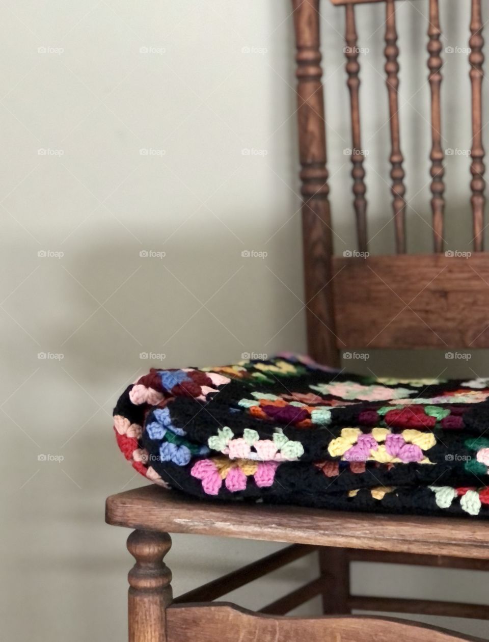 Focus on crochet blanket folded in antique wooden chair 