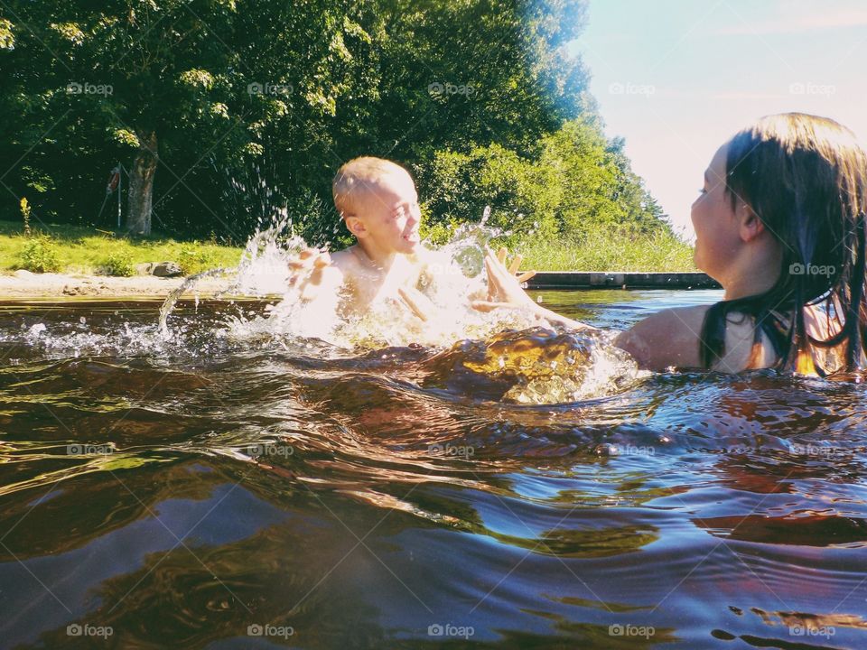 Children splashing water and having fun in the lake