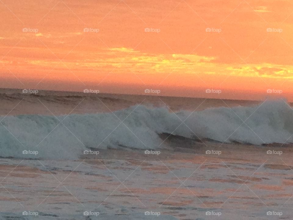 Glowing sky and rolling waves at sunset on Huntington Beach