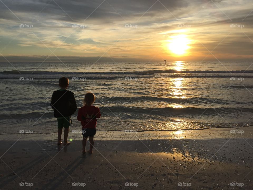 Kids watching the sunset on the beach 
