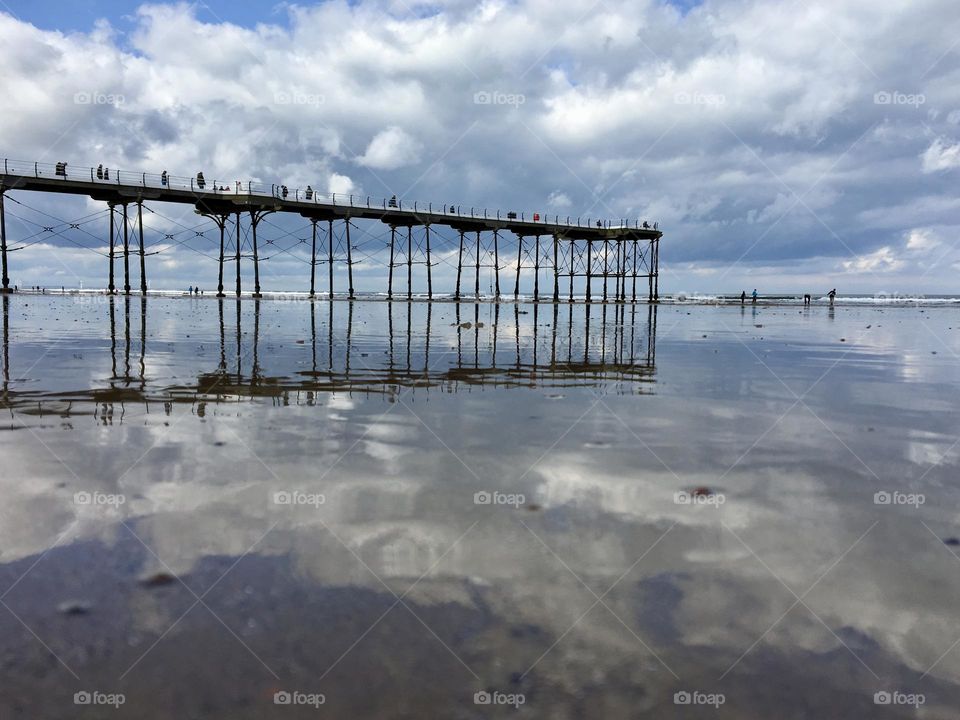 Cloudy day at the coast … tides out and beautiful reflections appear in the wet sand and puddles of sea water 