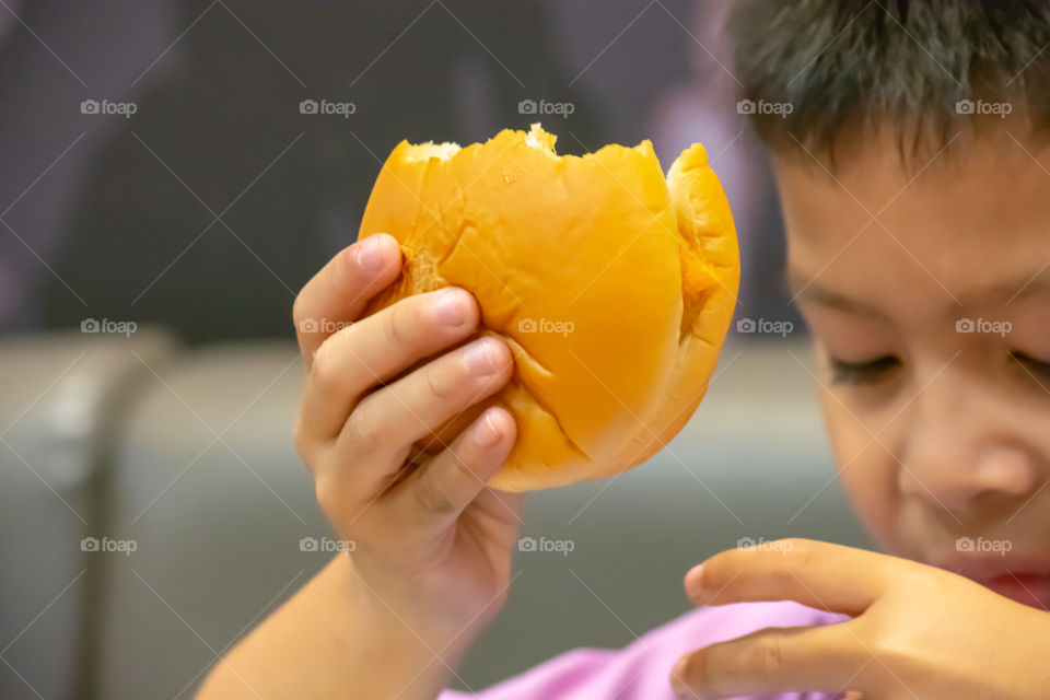 Hamburger fish in hand asia boy holding the eating.