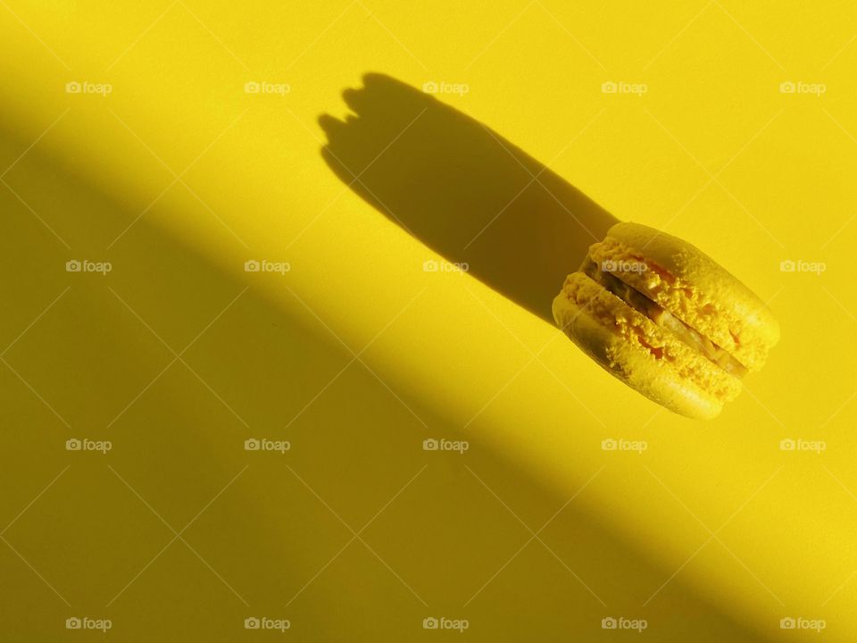 Yellow macaroon on yellow background 