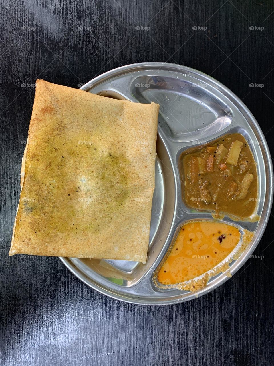 Masala dosa served in a plate with sambar and chutney 