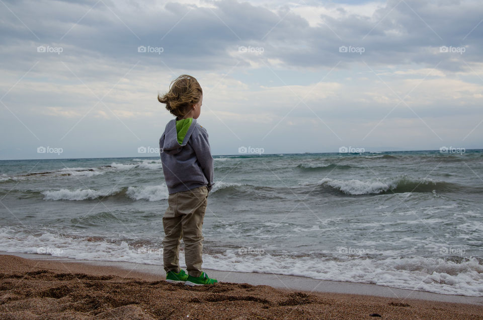 A Boy Standing on the Shore of Stormy Lake