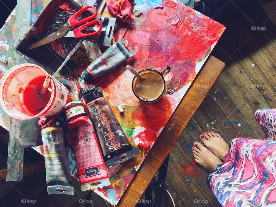 Morning coffee or drawing with bright colors? Feet view at drawing place full of colors