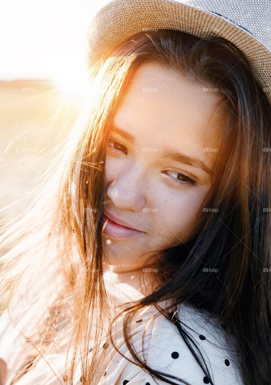 Close up portrait of a beautiful young woman. Sun rays through hair. Summer mood