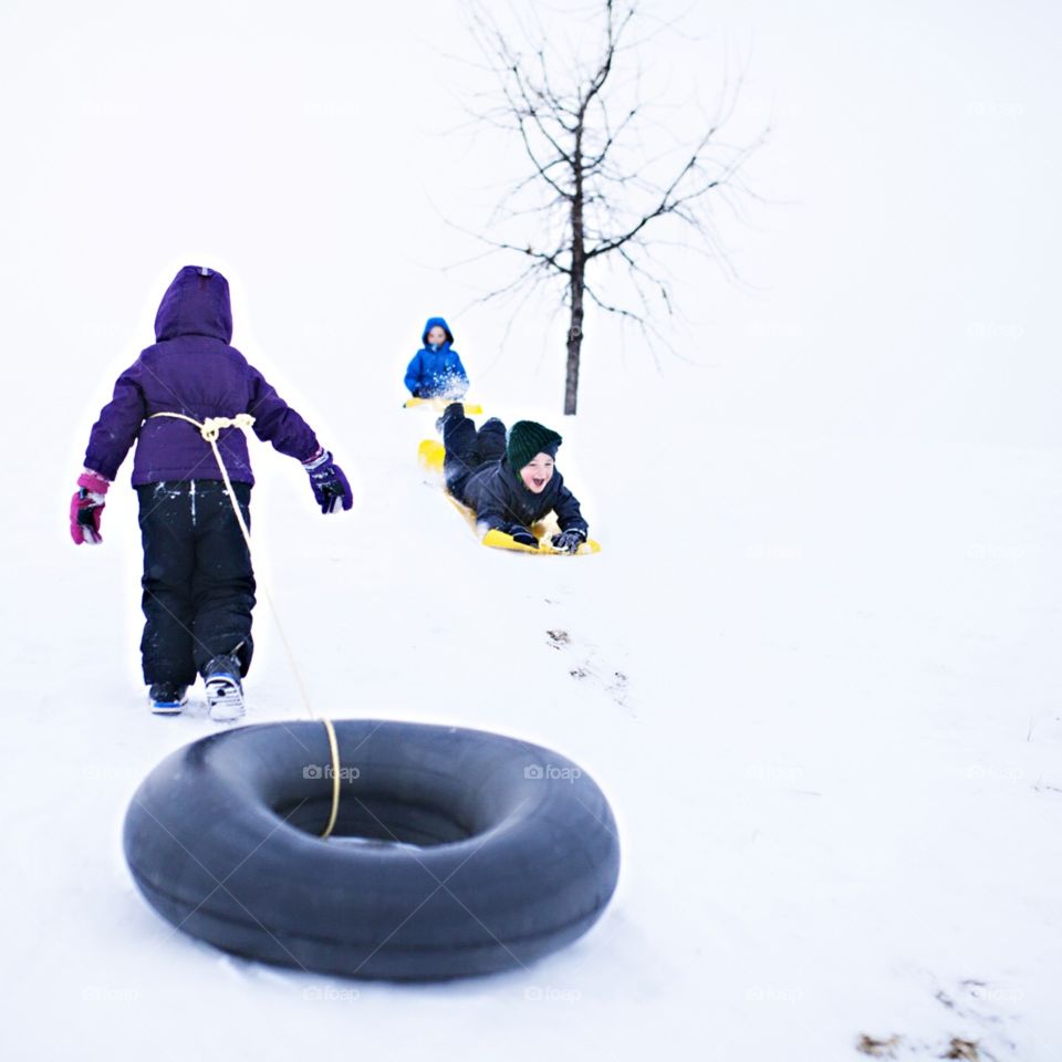 Kids sledding down a hill in the winter snow 