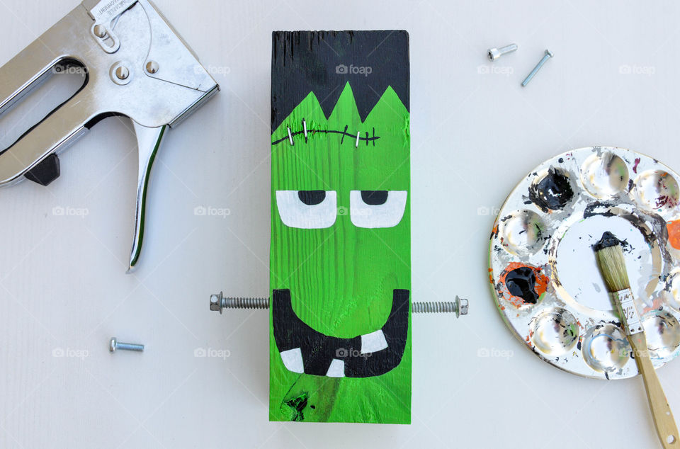 Making a frankenstein out of a wooden block with paint, bolts and staple gun laid out
